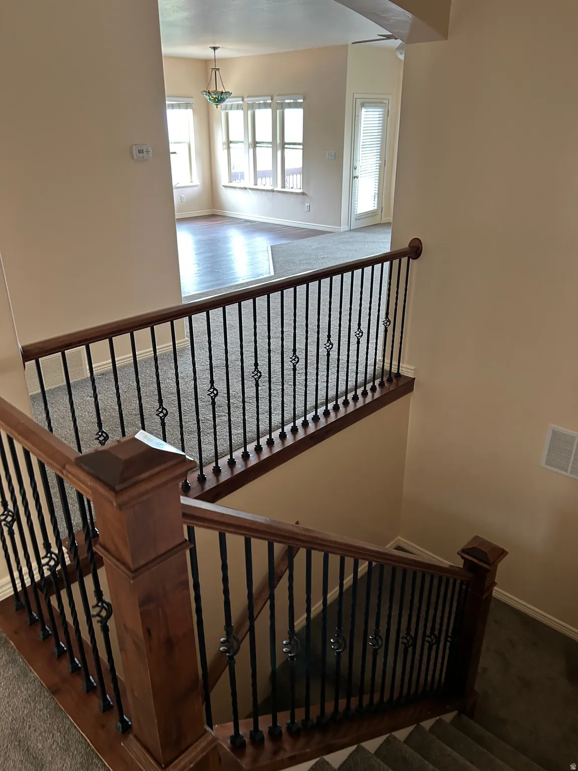 Staircase with wood-finish handrails and decorative wrought iron balusters