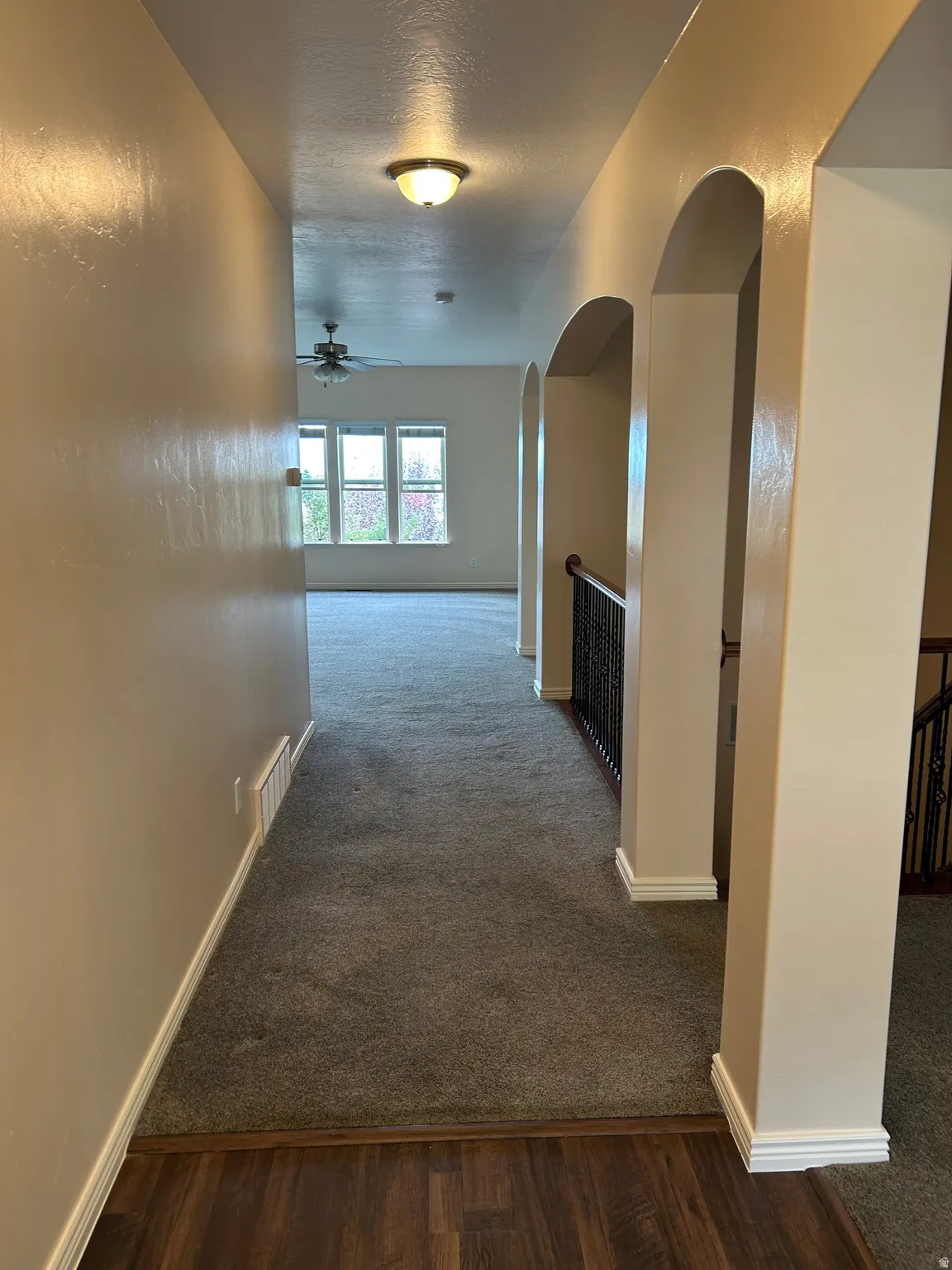 Hallway featuring wood-finish flooring, archways, and carpeted areas