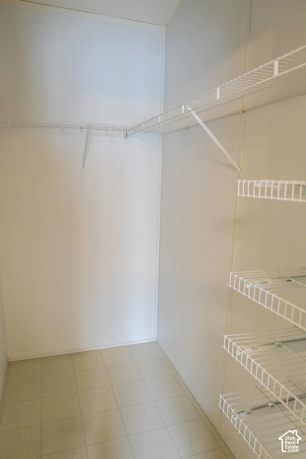 White wire shelving system, wall-mounted hanging rod, and tiled flooring