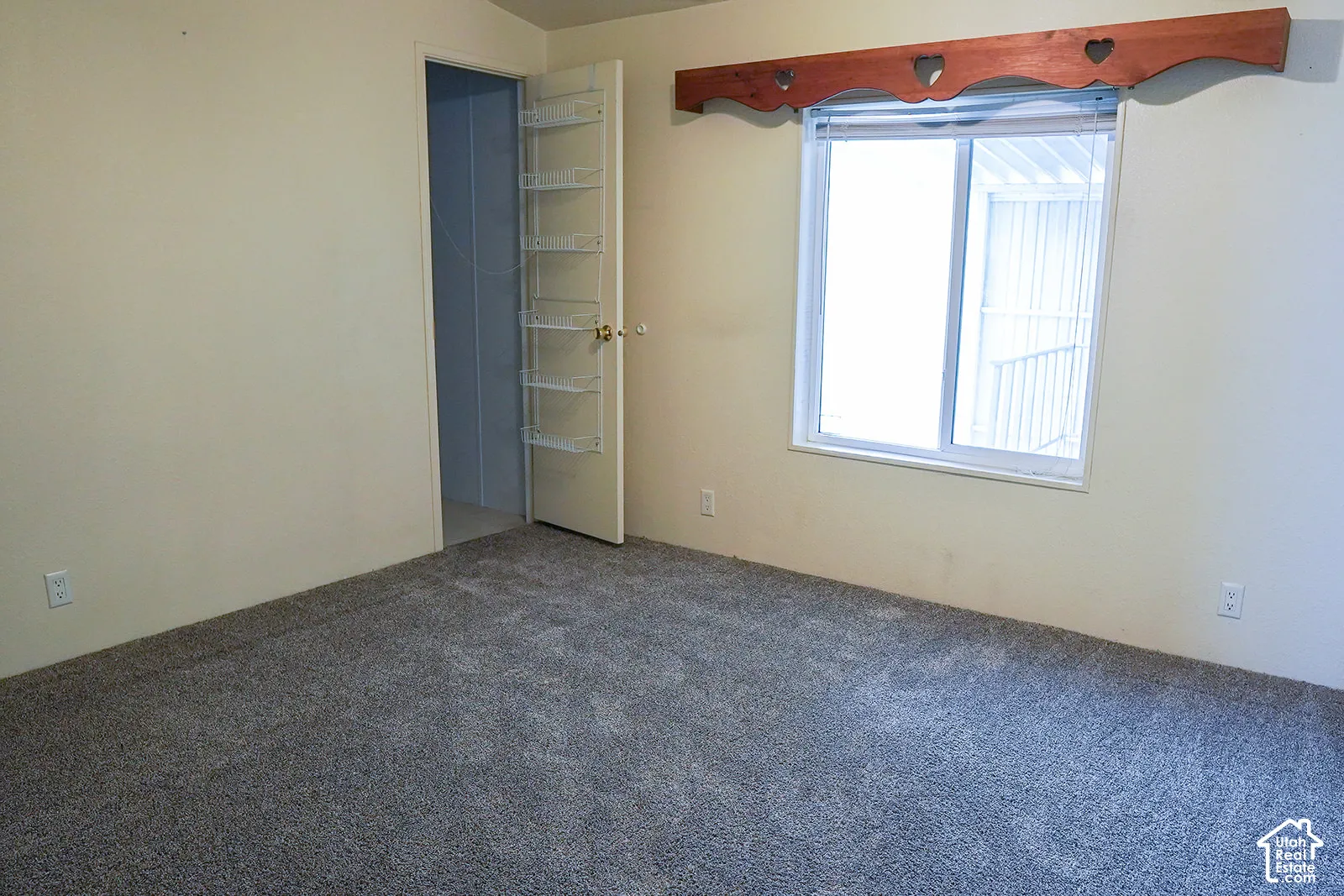 Neutral tone wall paint, gray carpeting, and a white window frame with a decorative valance