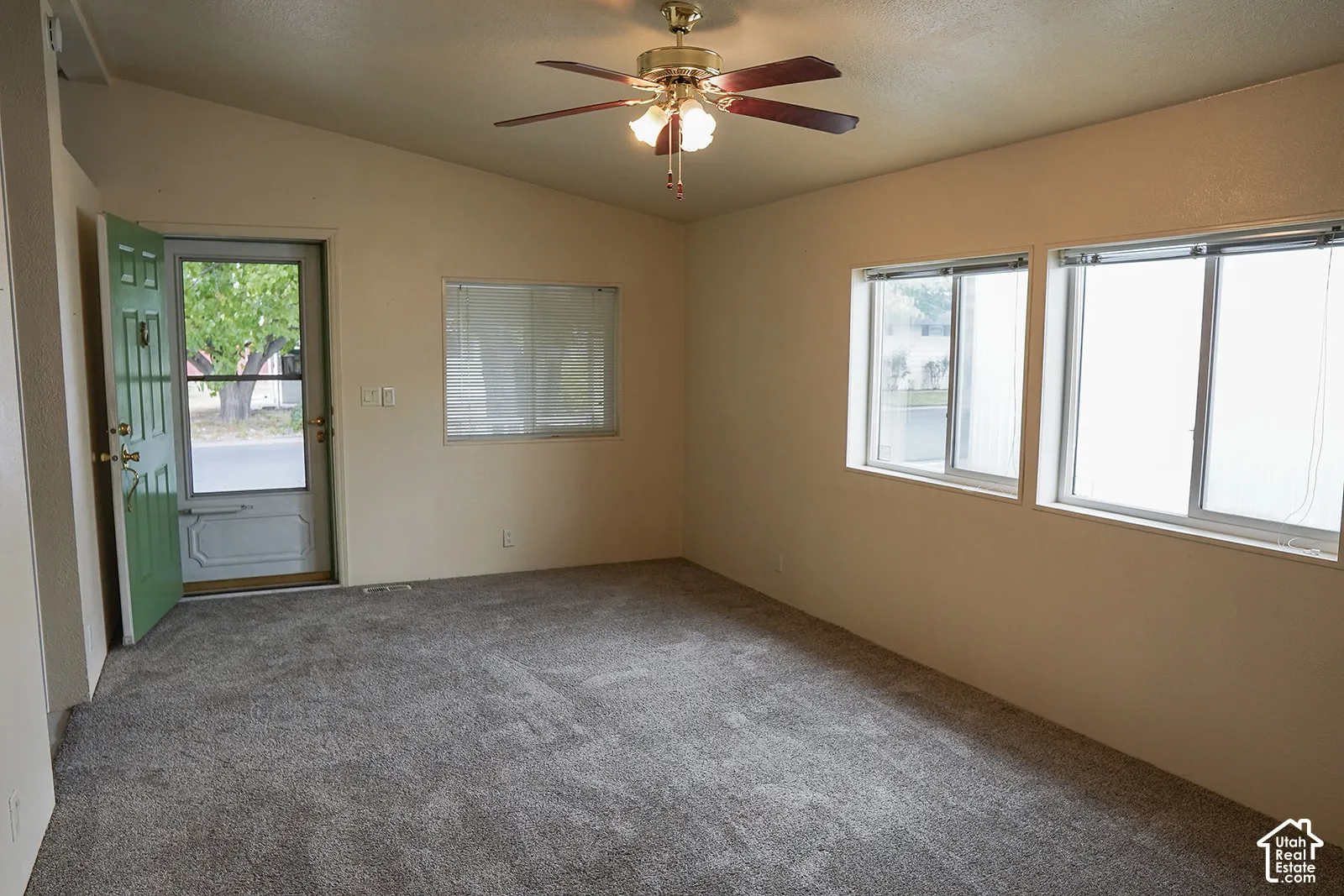 Vaulted ceiling with a ceiling fan light fixture, dual pane windows, and gray carpet flooring