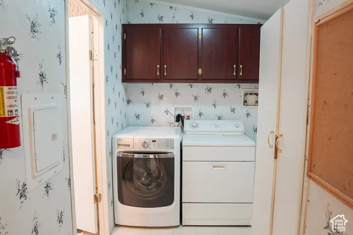 Laundry area featuring upper cabinetry, a front-load washer, and a top-load dryer