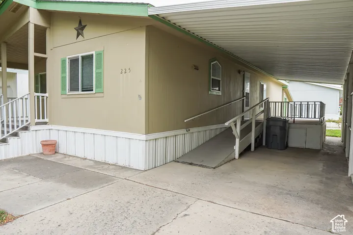 Covered carport with concrete surface, exterior siding, porch with steps, and an access ramp
