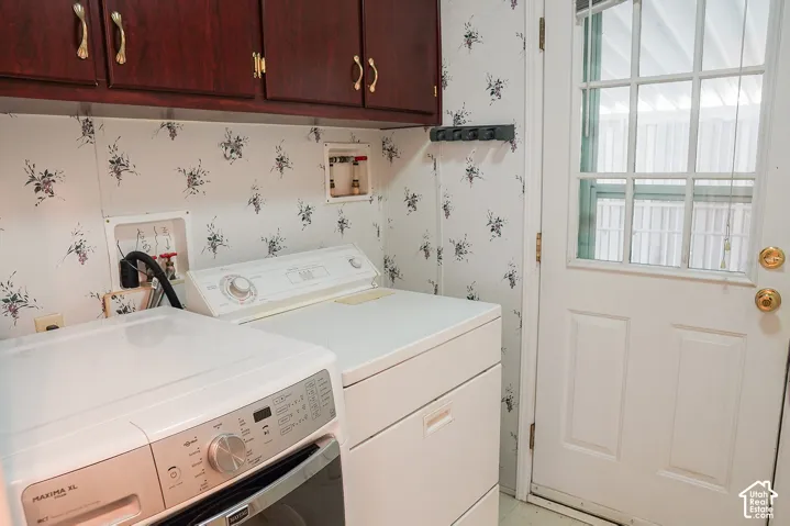 Built-in cabinetry with brass hardware, patterned wallpaper, and a white paneled door with glass inserts