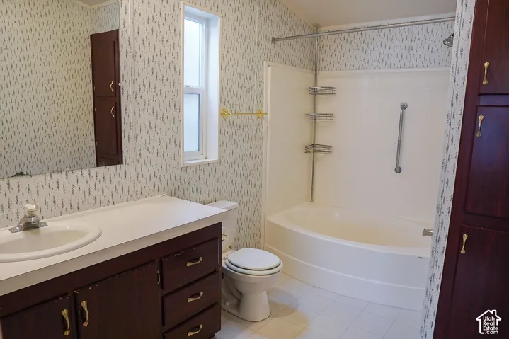Dark wood-finish vanity with an integrated sink and white countertop, full-width wall mirror, and a white bathtub with an overhead shower