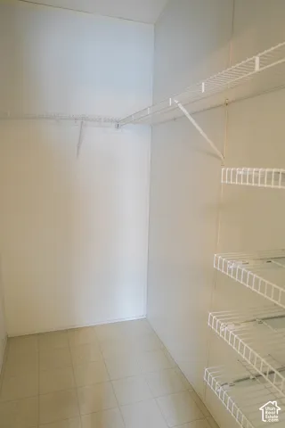 White wire shelving system, wall-mounted hanging rod, and tiled flooring