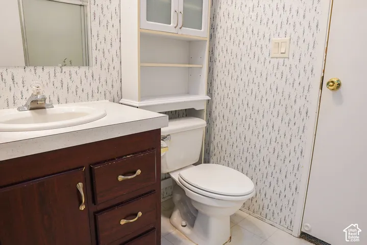 Bathroom featuring a dark wood-finish vanity with an integrated sink, an overhead wall cabinet, and a white toilet