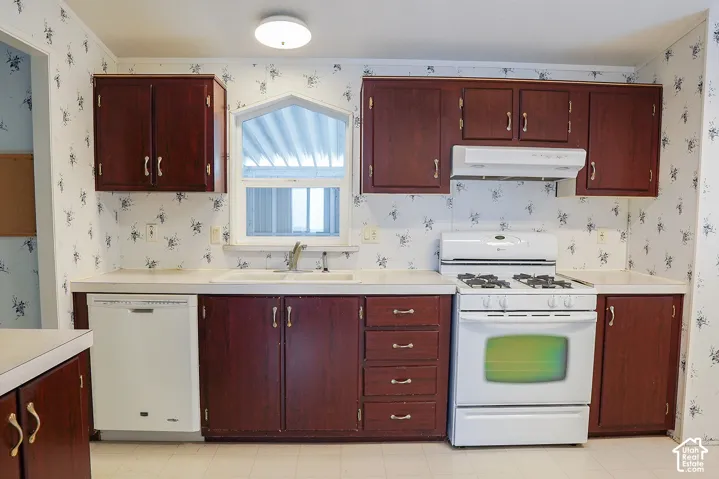 Kitchen featuring wood-finish cabinetry, a double basin sink, a built-in dishwasher, and a gas range