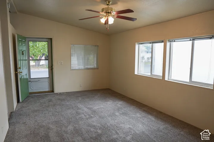 Vaulted ceiling with a ceiling fan light fixture, dual pane windows, and gray carpet flooring
