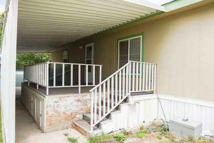 Covered entry featuring a white aluminum railing system, concrete foundation with stone veneer accents, and a metal roof overhang
