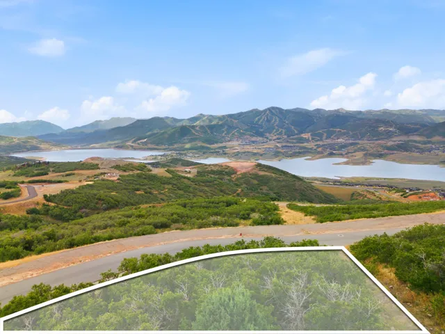 Mountain landscape with a substantial body of water, distant hills, and a paved road