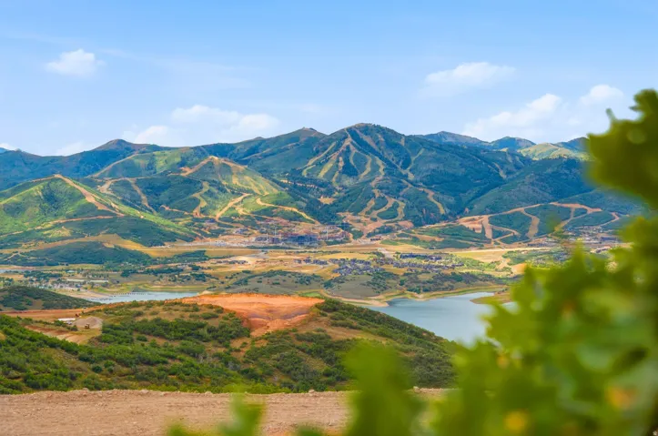Expansive mountain range, bodies of water, and distant residential structures