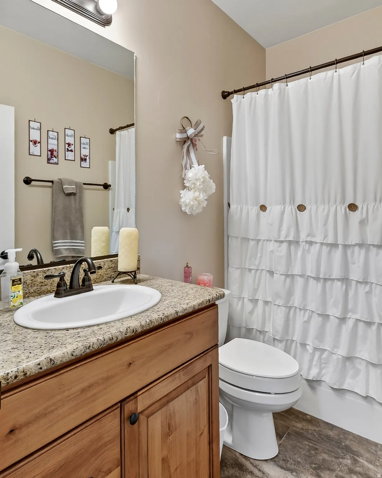 Spa-inspired bathroom featuring a wood-finish vanity with granite countertop, round undermount sink, and oil-rubbed bronze hardware
