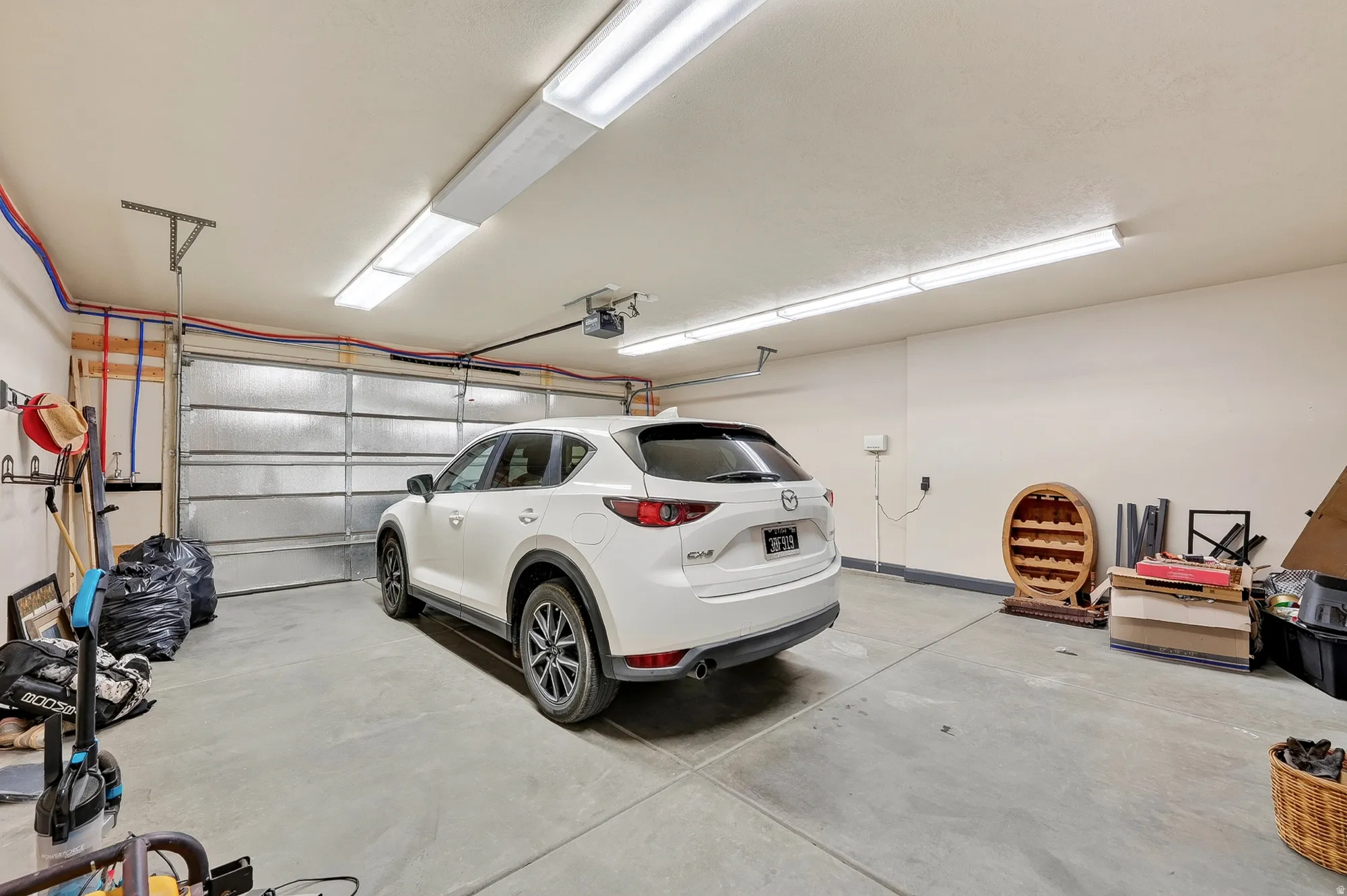 Spacious attached garage featuring epoxy-finished concrete flooring, overhead LED lighting, and sectional garage door