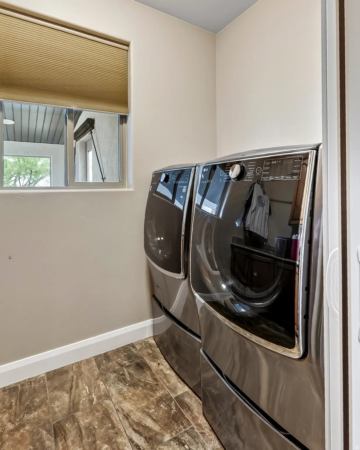 Modern laundry room featuring premium front-load washer and dryer with sleek dark stainless steel finishes and illuminated control panels