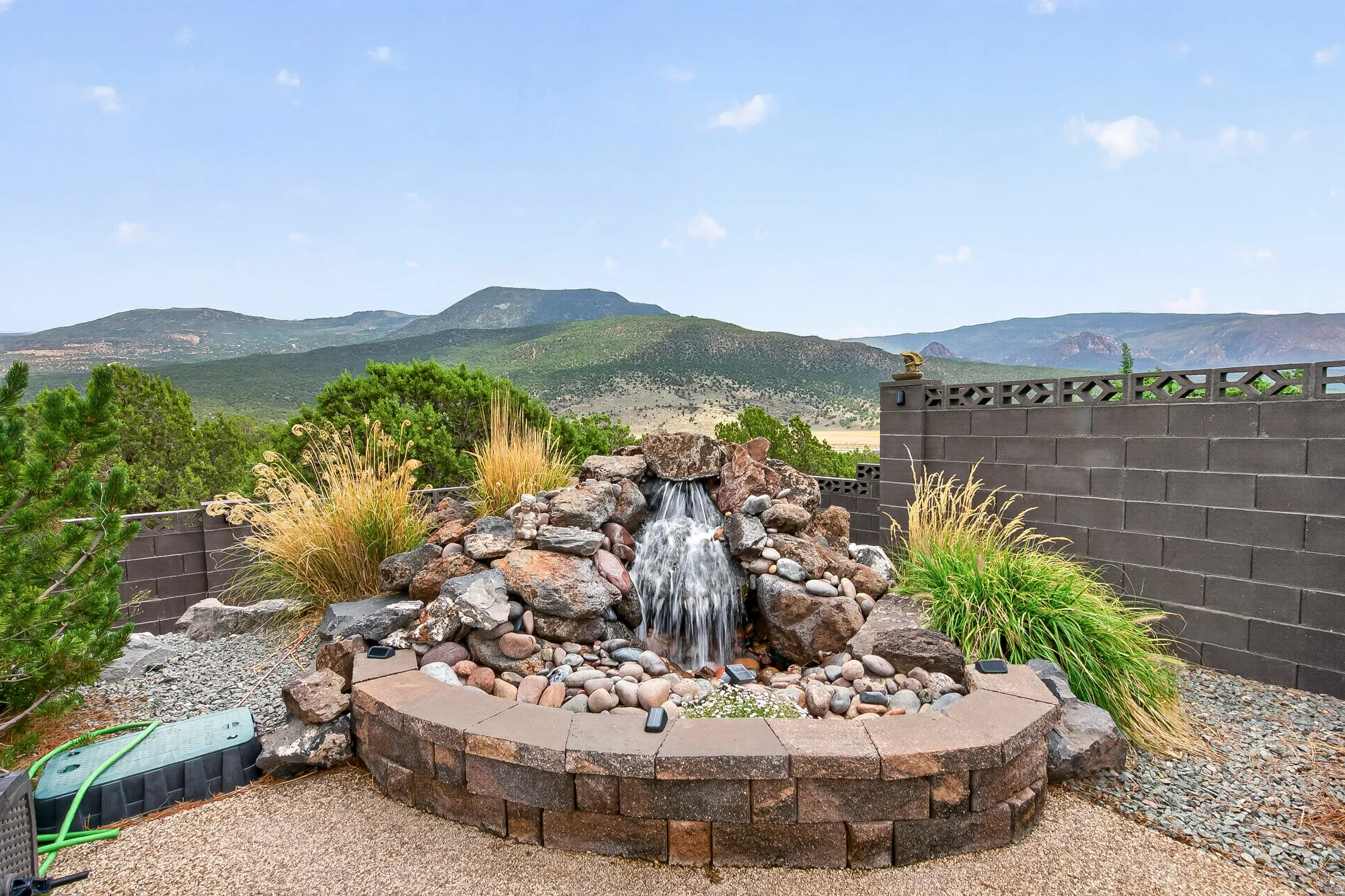 Backyard oasis featuring a custom stone-lined water feature with cascading waterfall, decorative rock landscaping, and ornamental grasses