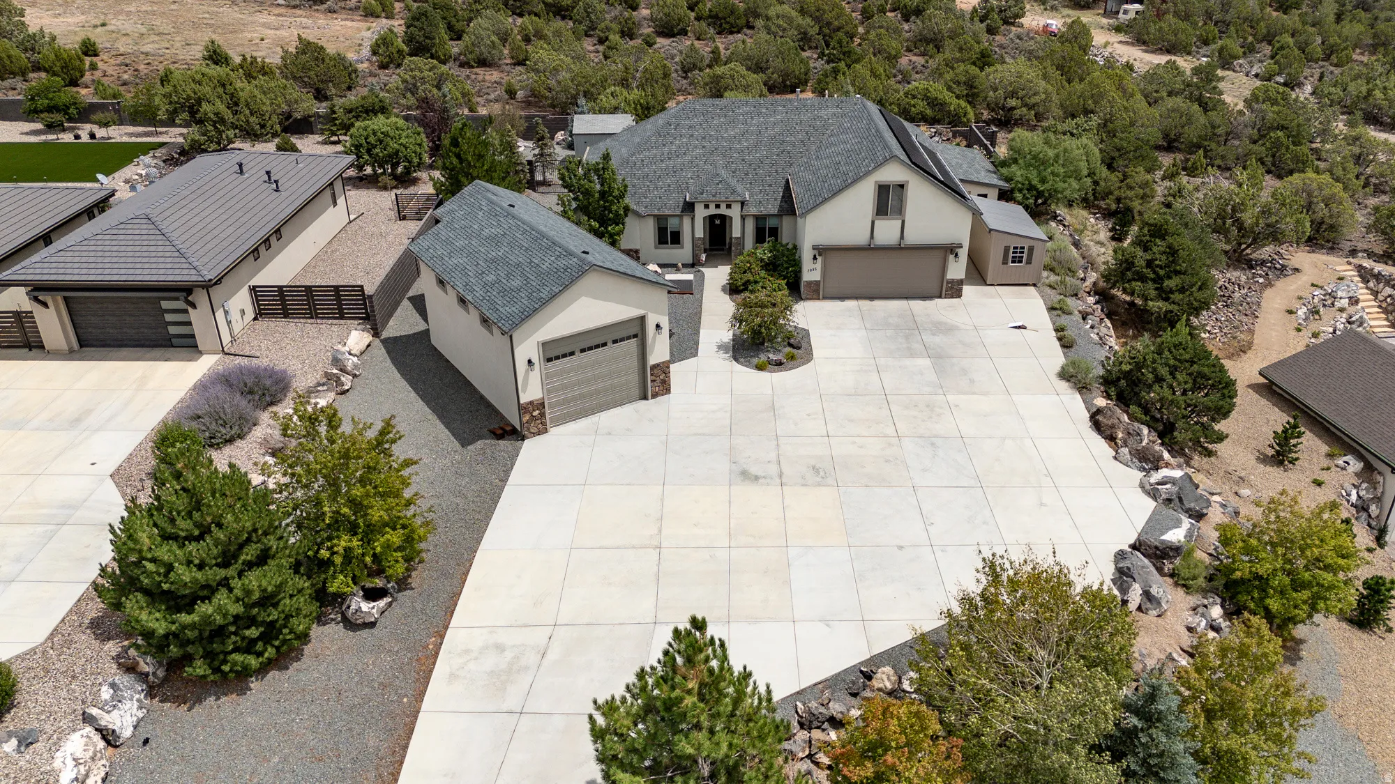 Expansive paved driveway, attached two-car garage, detached single-car garage, stucco exterior, and stone accents