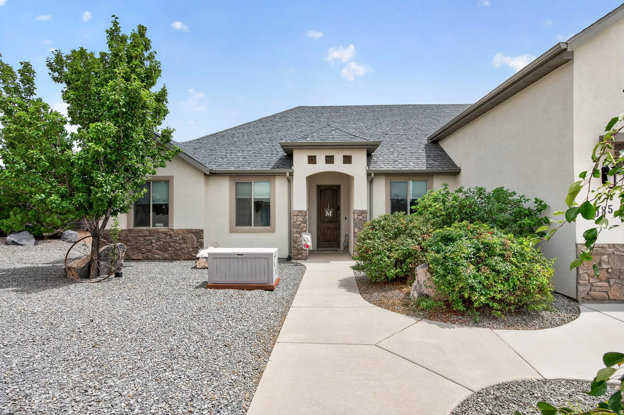 Stucco exterior with stone accents, covered entry, and a paved walkway