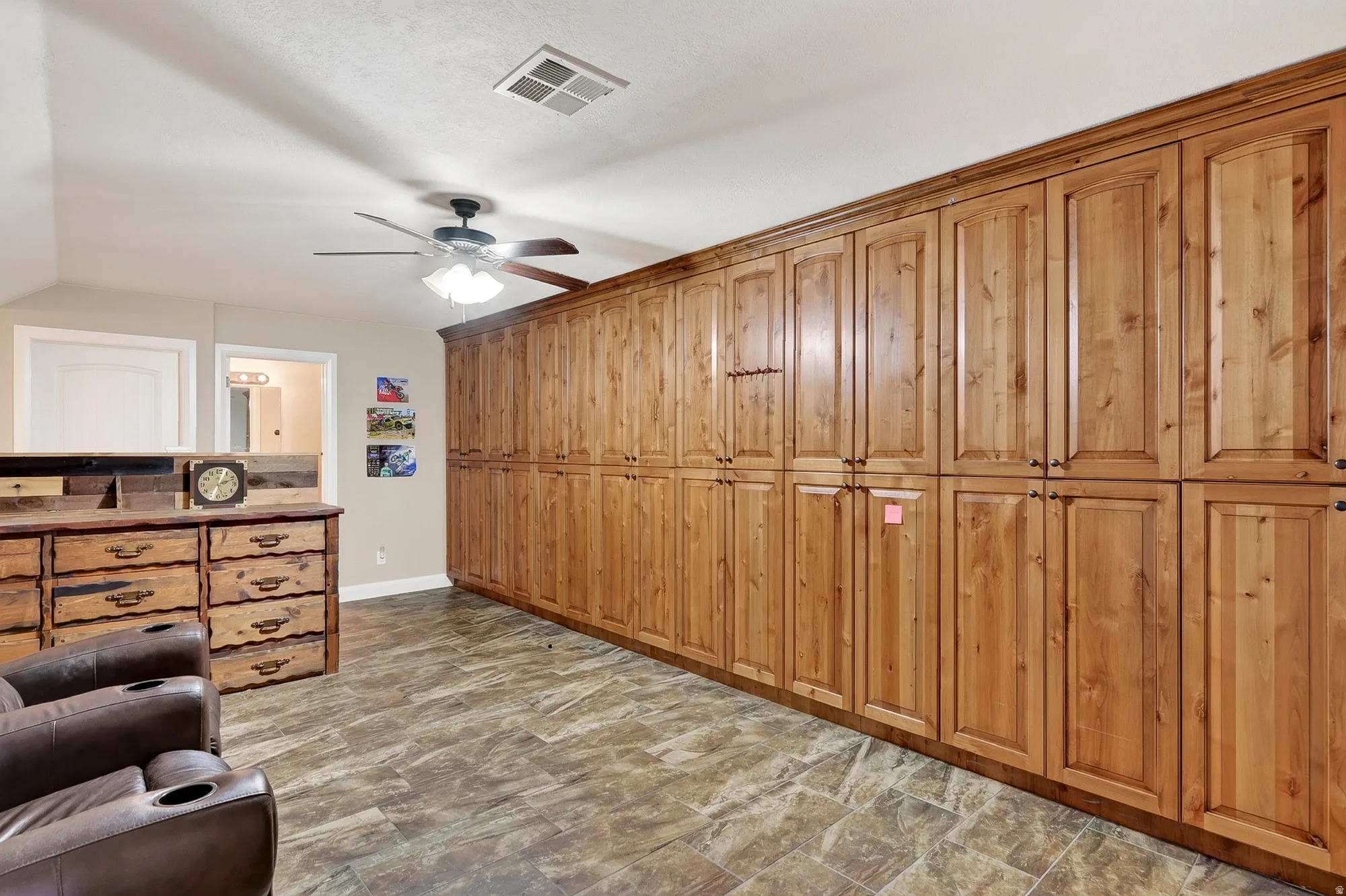 Extensive custom cabinetry, wood-finish flooring, ceiling fan with integrated lighting, and neutral wall paint