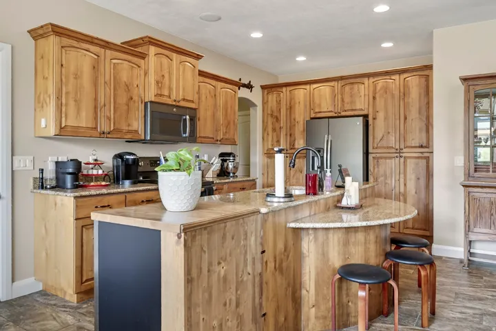 Warm wood cabinetry with arched crown molding throughout the kitchen, complemented by stainless steel appliances and a dual-level island featuring wood-finish countertops