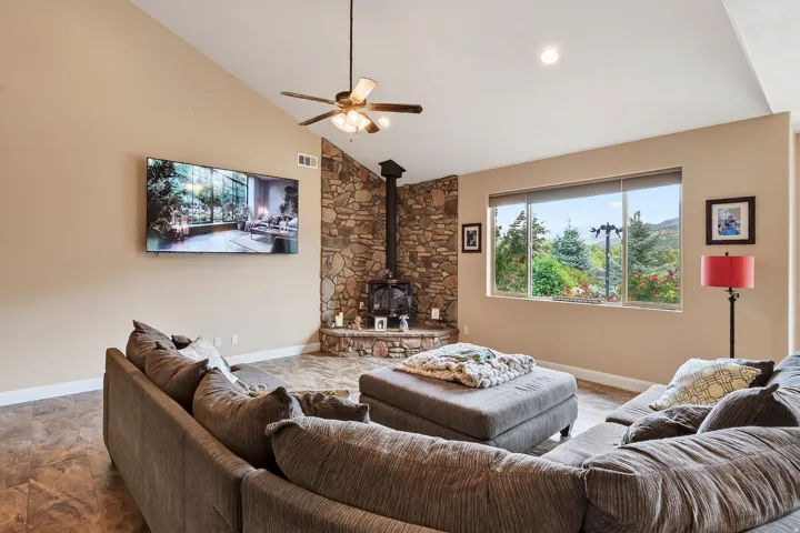 Spacious great room showcasing vaulted ceilings, ceiling fan, and abundant natural light from large windows
