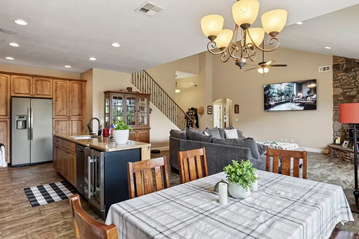 Open-concept living area featuring a wood-finish kitchen with stainless steel appliances, wood cabinetry, and a center island with seating