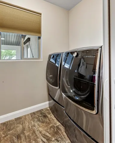 Modern laundry room featuring premium front-load washer and dryer with sleek dark stainless steel finishes and illuminated control panels