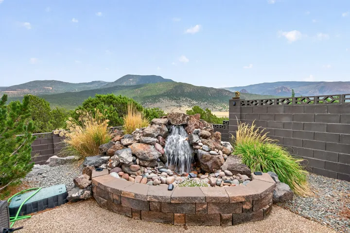 Backyard oasis featuring a custom stone-lined water feature with cascading waterfall, decorative rock landscaping, and ornamental grasses