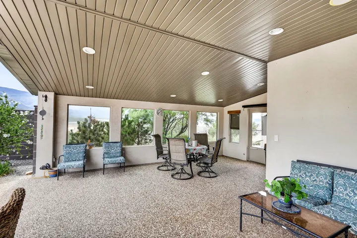 Bright sunroom featuring extensive glass panels, wood-finish plank ceiling with recessed lighting, polished concrete flooring, and direct outdoor access