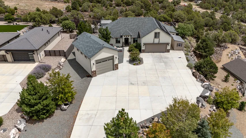 Expansive paved driveway, attached two-car garage, detached single-car garage, stucco exterior, and stone accents