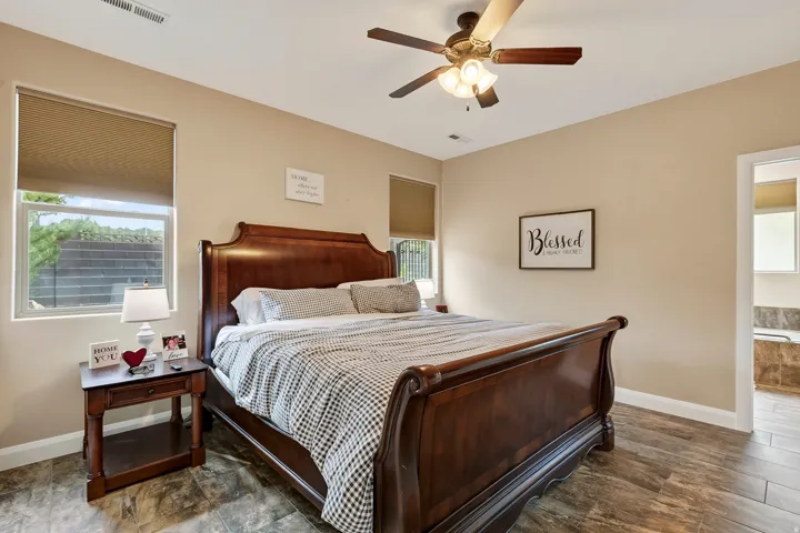 Master bedroom featuring a wood-finish sleigh bed, ceiling fan with integrated lighting, and wood-finish flooring
