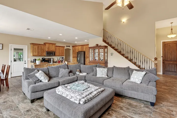 Open-concept living area featuring a sectional arrangement anchored by a wood-finish plank floor, recessed ceiling lighting, and direct sightlines to the kitchen