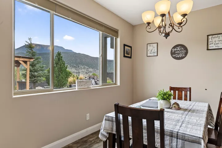 Dining area bathed in natural light through expansive multi-pane windows framing mountain scenery
