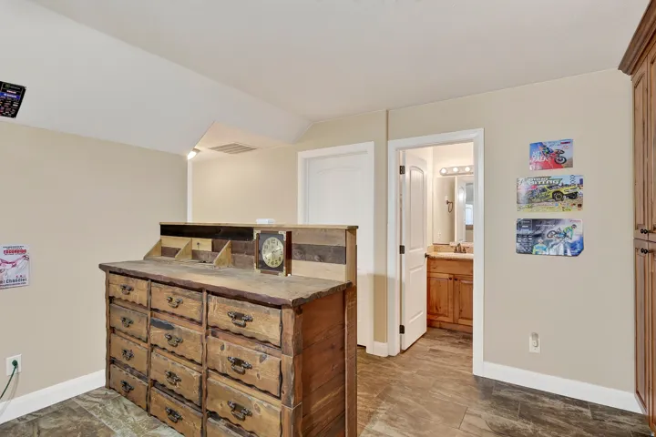 Bedroom featuring hardwood flooring, abundant natural light from multiple windows, and a spacious wooden dresser with brass hardware