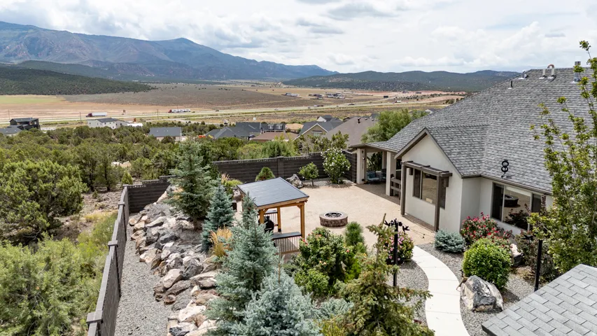 Modern residence featuring a expansive paved terrace with integrated landscaping, contemporary architectural design with clean lines and mixed exterior finishes, mature specimen trees and drought-tolerant plantings throughout the grounds, and commanding v