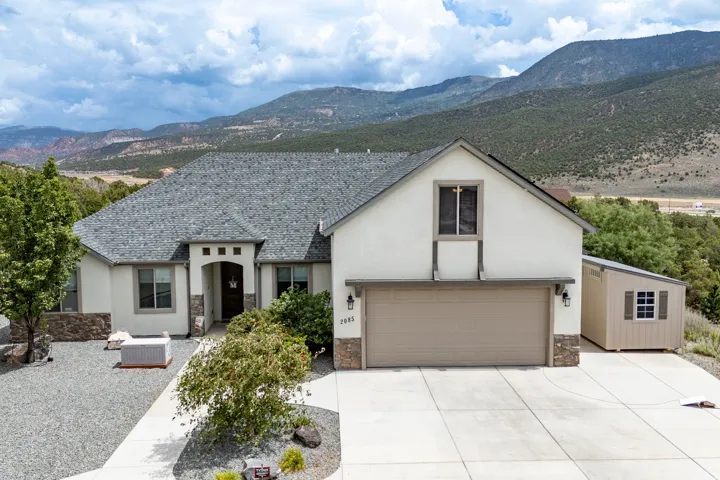 Modern single-story residence featuring a clean-lined stucco exterior with stone accents, pitched roofline with dimensional asphalt shingles, and a two-car attached garage with a neutral-finish door
