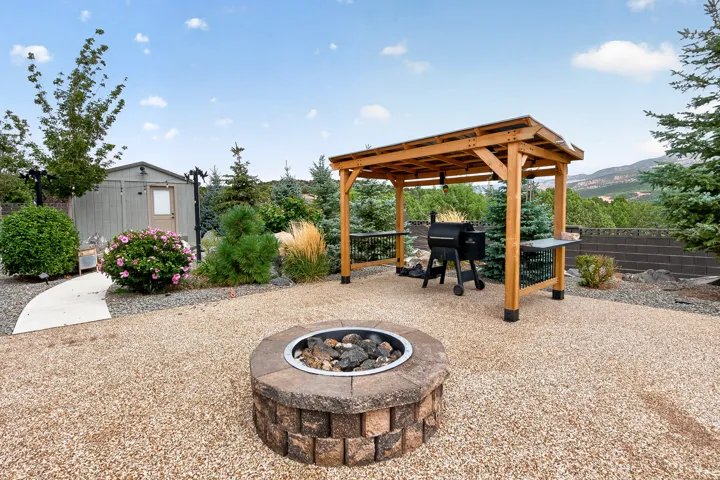 Outdoor living space featuring a fire pit, a wooden pergola, and a gravel-covered ground surface