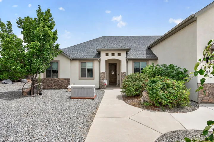 Stucco exterior with stone accents, covered entry, and a paved walkway