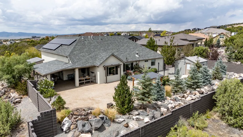 Modern residence showcasing a composite shingle roof, professional landscaping with mature evergreens and decorative stone hardscaping, a three-car attached garage with covered entry, and expansive concrete driveway