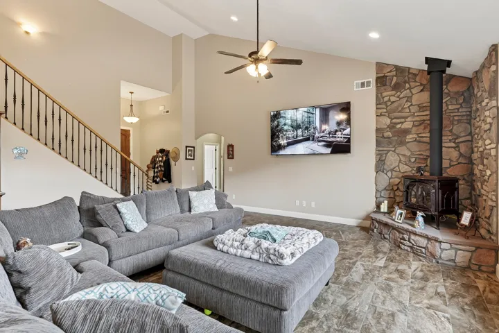 Open-concept living space with soaring ceilings, ceiling fan with integrated lighting, and a curved sectional layout