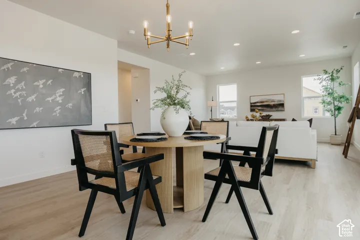 Open-concept living area featuring a dining space with a modern chandelier and wood-finish flooring