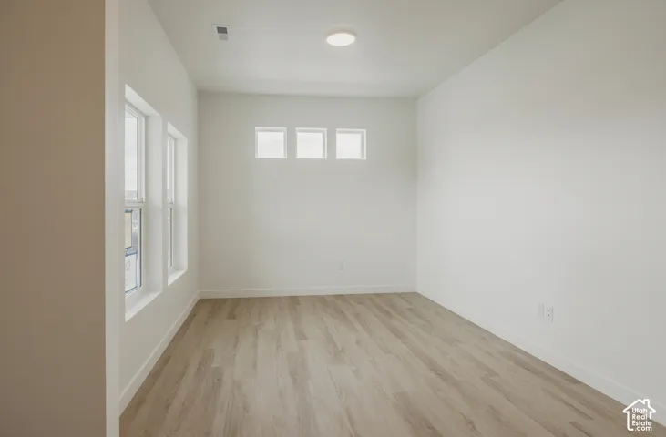 Crisp white walls, wood-finish flooring, recessed lighting, and multiple windows define this versatile space