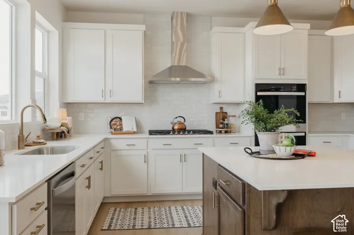 White cabinetry, stainless steel appliances, built-in double oven, U-shaped countertop, and an island with a light-toned surface