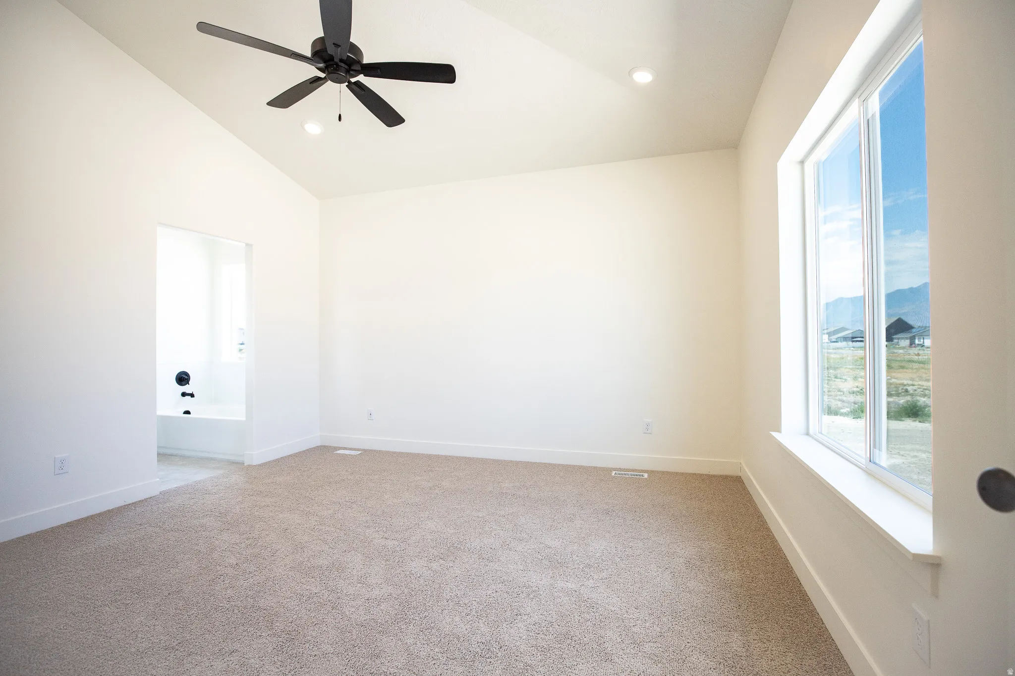 Primary bedroom with vaulted ceiling and ceiling fan.