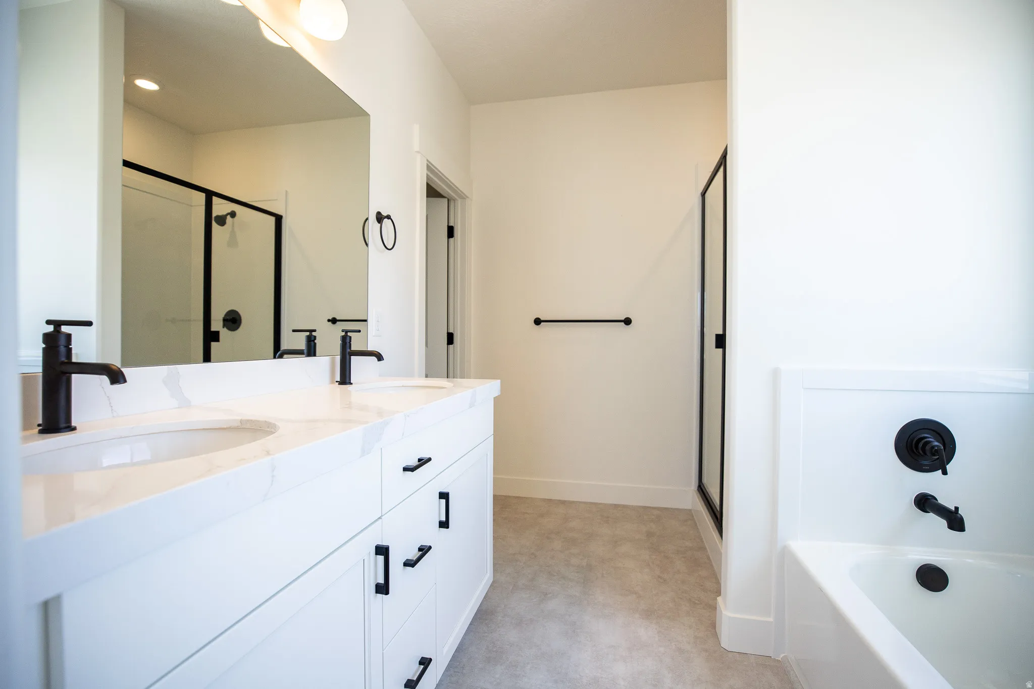 Primary bath with dual sinks, painted white wood cabinets, quartz slab countertop, soaker tub and large walk-in shower.