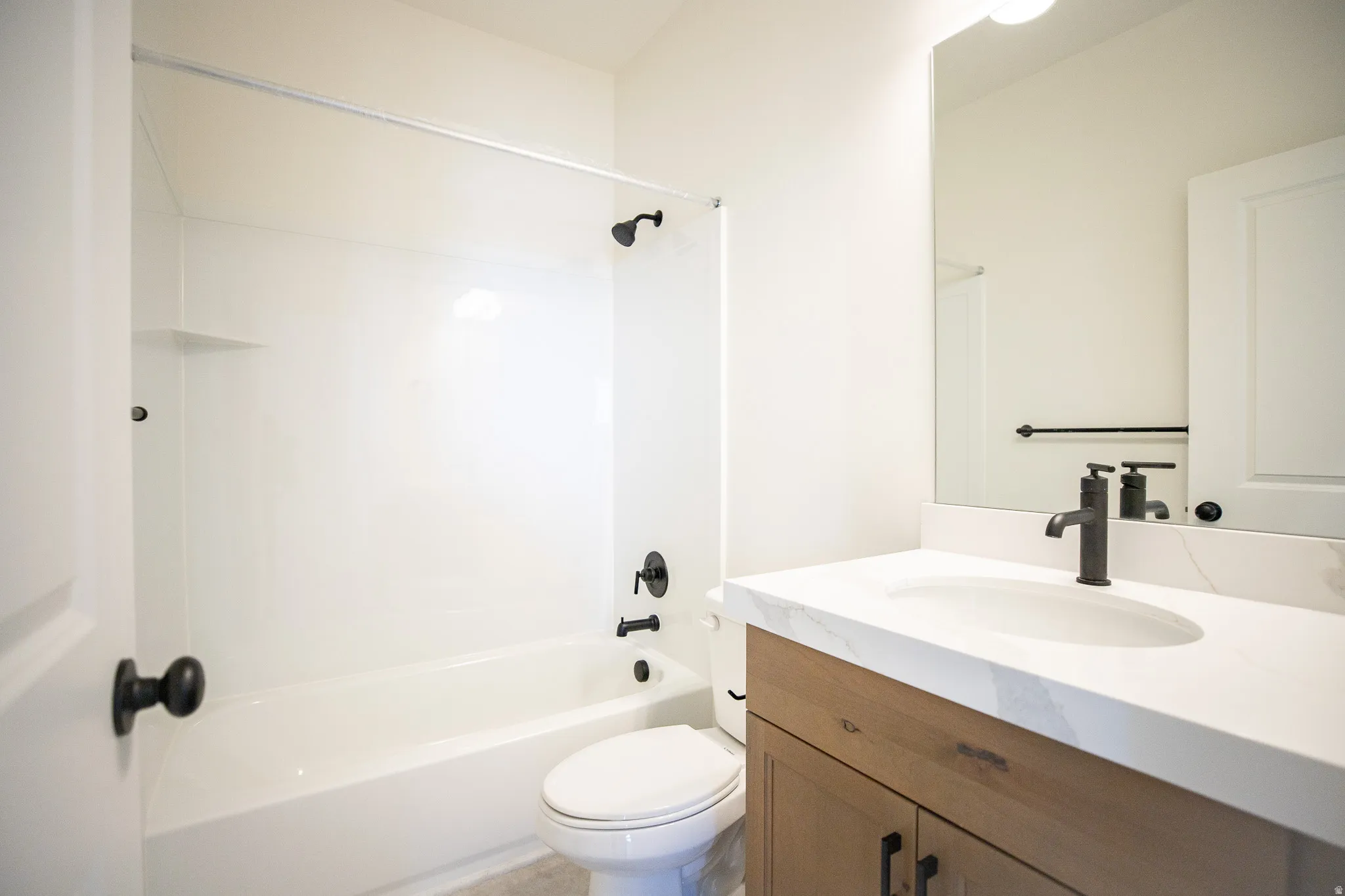Full secondary bath with stained wood cabinets and quartz slab countertops.