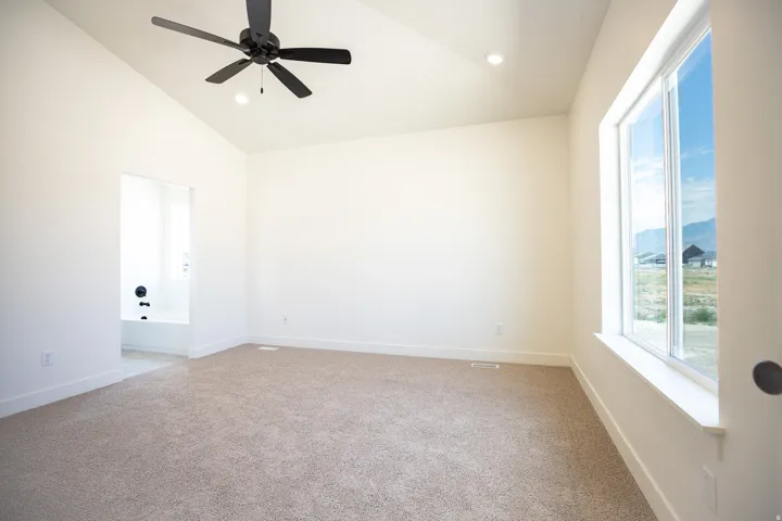 Primary bedroom with vaulted ceiling and ceiling fan.