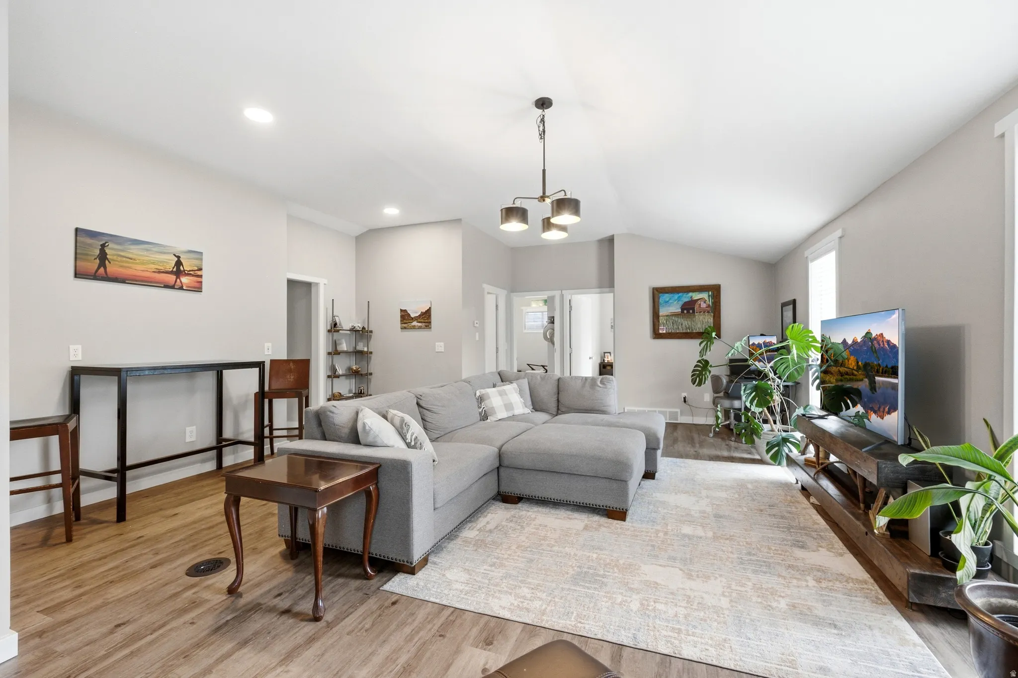 Spacious living area featuring vaulted ceilings, wood-finish flooring, and recessed lighting