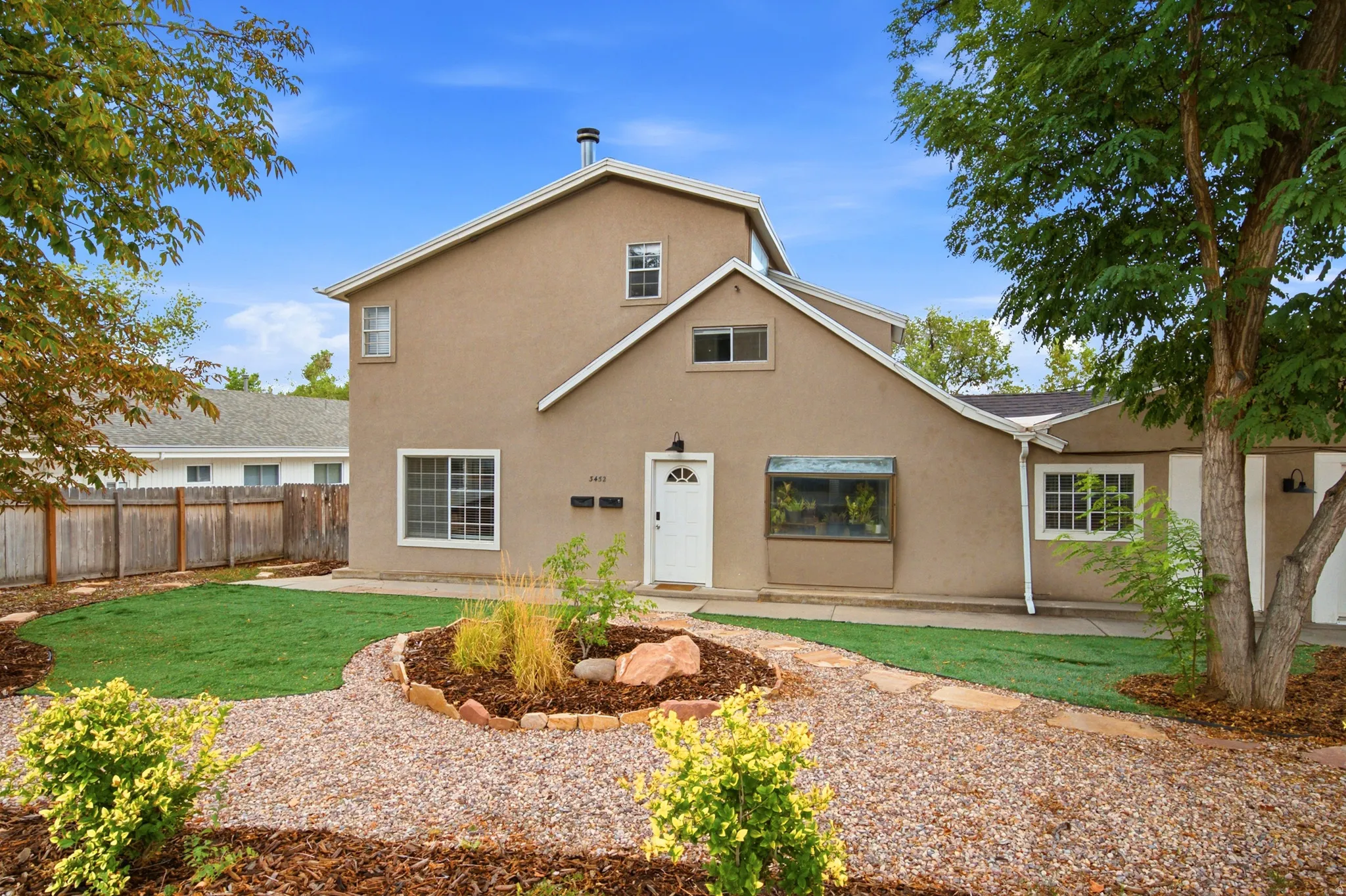Stucco exterior with multiple window styles, central front door, and a bay window feature