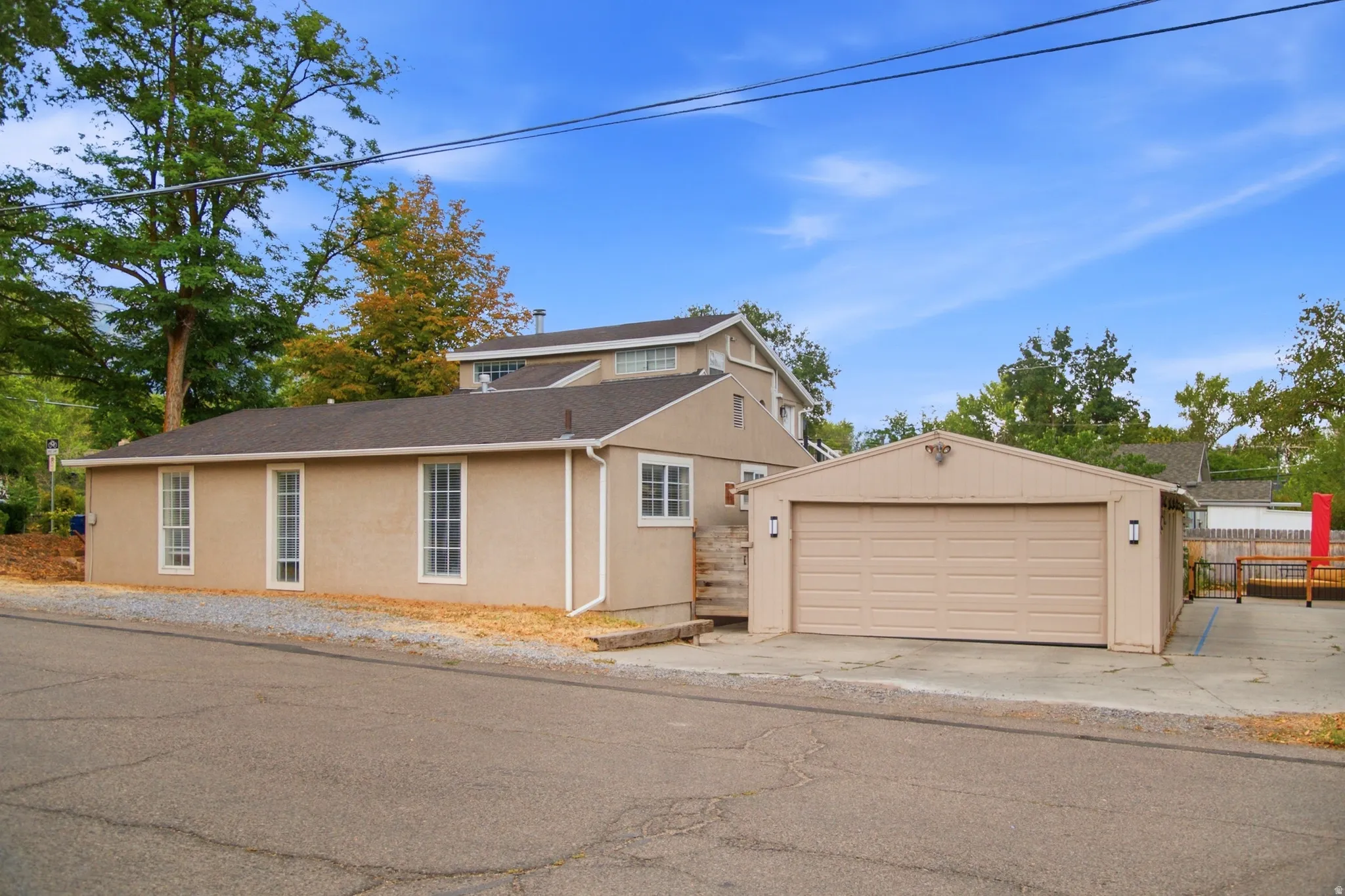 Stucco exterior with multiple windows, attached two-car garage, and a gravel driveway